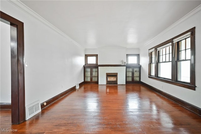 unfurnished living room with wood finished floors, ornamental molding, a brick fireplace, and baseboards