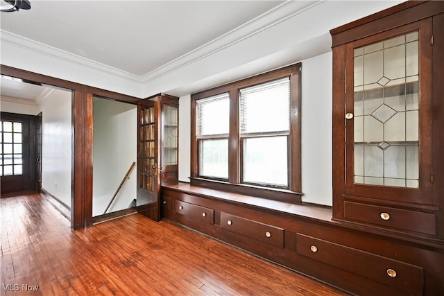empty room featuring crown molding, dark wood-type flooring, and baseboards