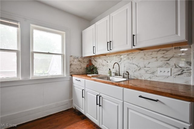 kitchen with butcher block countertops, a sink, white cabinetry, tasteful backsplash, and dark wood-style flooring