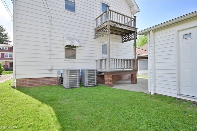 rear view of property featuring a balcony, central AC unit, and a yard