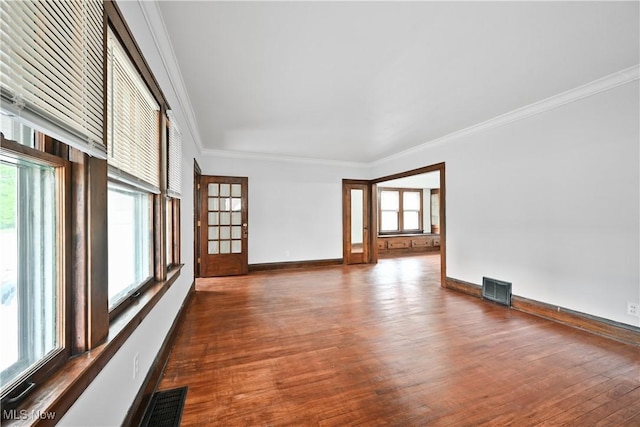 empty room with wood finished floors, ornamental molding, and baseboards