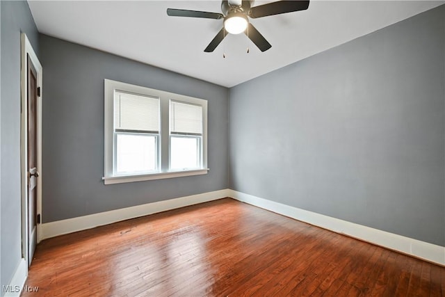 empty room featuring wood-type flooring, baseboards, and a ceiling fan