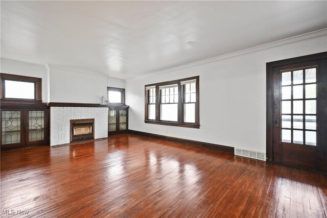 unfurnished living room featuring hardwood / wood-style floors, crown molding, a fireplace, and baseboards
