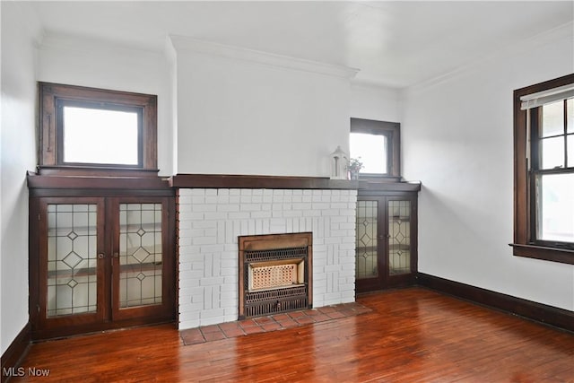 unfurnished living room with a fireplace, crown molding, wood finished floors, healthy amount of natural light, and baseboards