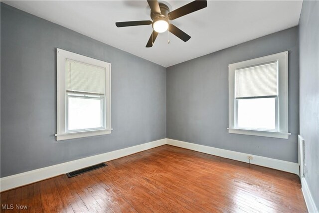spare room featuring hardwood / wood-style floors, baseboards, and plenty of natural light