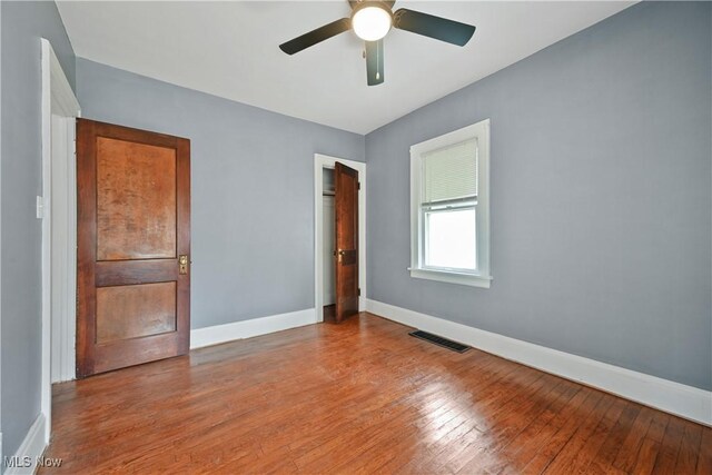 unfurnished bedroom with baseboards, hardwood / wood-style flooring, a closet, and ceiling fan