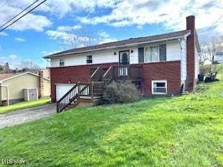 116 Brentwood Blvd, Wintersville, OH 43953 - rear view of house featuring a chimney, a garage, asphalt driveway, a lawn, and brick siding