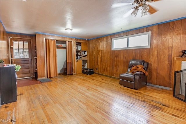 unfurnished room featuring hardwood / wood-style flooring, wooden walls, and a ceiling fan