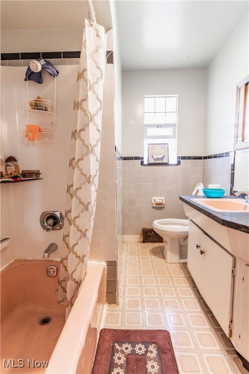 full bath featuring shower / tub combo with curtain, toilet, tile walls, a wainscoted wall, and vanity