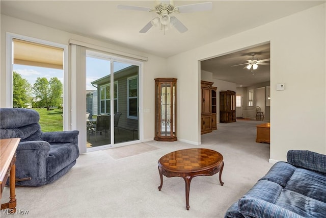 carpeted living area with a ceiling fan, healthy amount of natural light, and baseboards