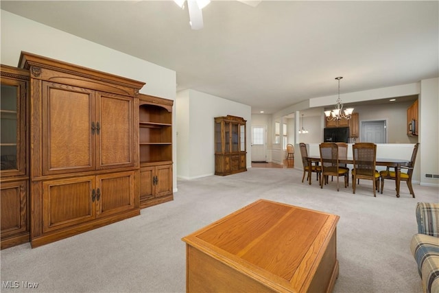 living room featuring light colored carpet, a chandelier, a ceiling fan, and baseboards