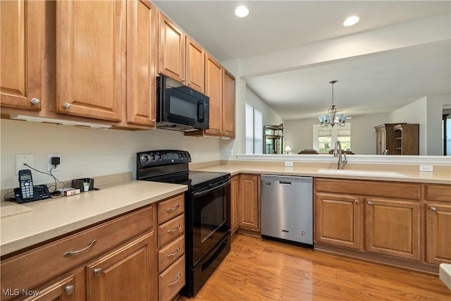kitchen with black appliances, a sink, light wood-type flooring, a chandelier, and brown cabinets