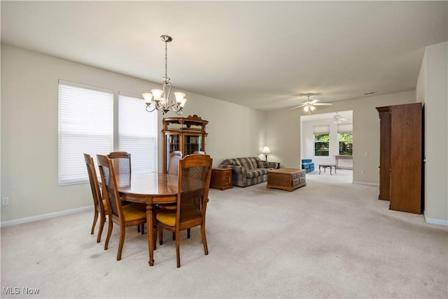 dining area featuring a chandelier, light colored carpet, baseboards, and ceiling fan