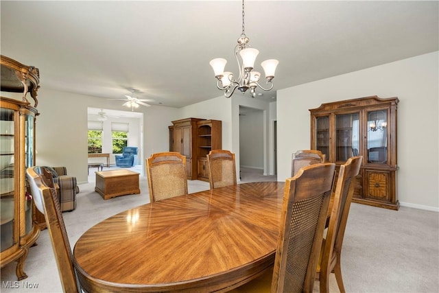 dining space with a chandelier, light colored carpet, and a ceiling fan