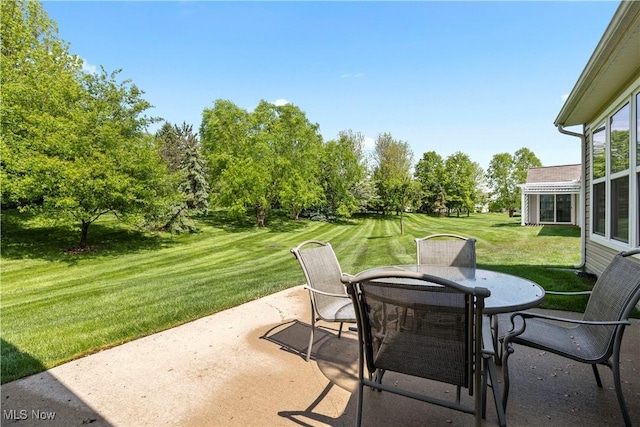 view of patio / terrace featuring outdoor dining area and view of wooded area