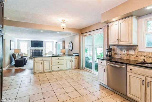 37 Monticello Dr, Brunswick, OH 44212 - kitchen featuring dishwasher, open floor plan, dark countertops, a stone fireplace, and backsplash