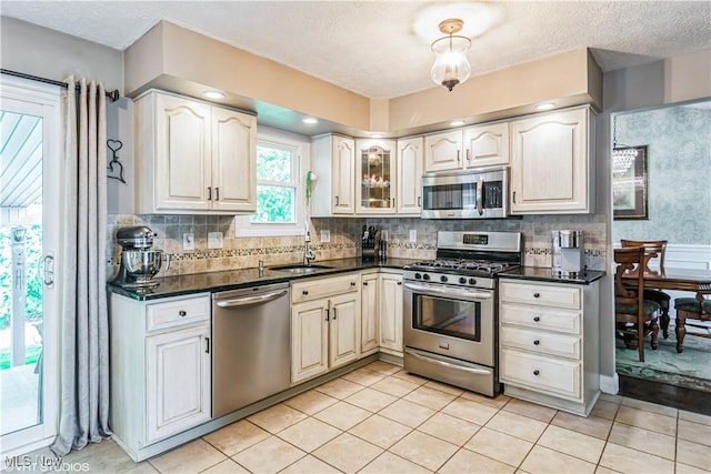 37 Monticello Dr, Brunswick, OH 44212 - kitchen with appliances with stainless steel finishes, dark countertops, a sink, backsplash, and a textured ceiling