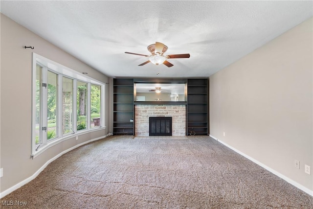 unfurnished living room featuring baseboards, carpet floors, ceiling fan, a fireplace, and a textured ceiling