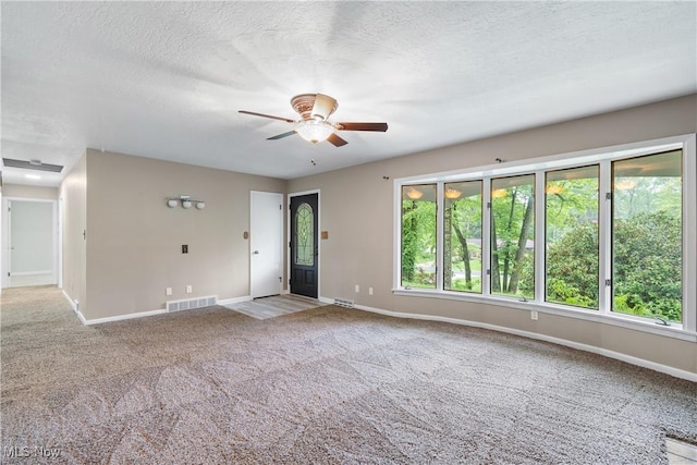 unfurnished living room with ceiling fan, baseboards, carpet flooring, and a textured ceiling