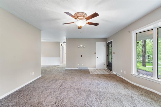 carpeted empty room with a ceiling fan and baseboards