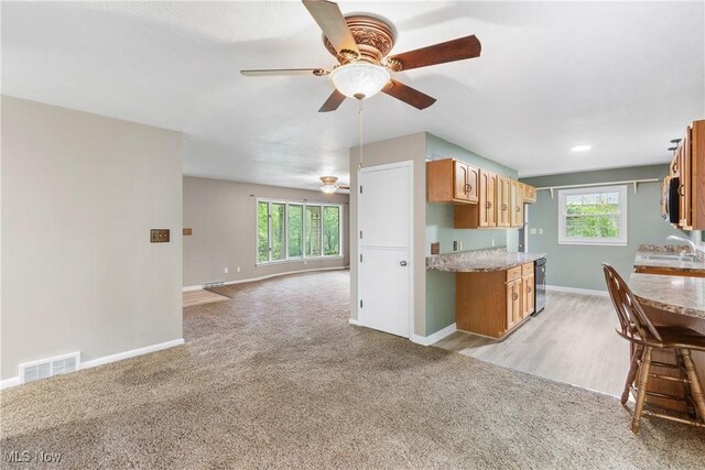 kitchen featuring a ceiling fan, baseboards, light colored carpet, and healthy amount of natural light