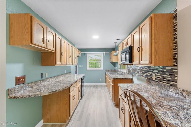 kitchen with black microwave, a sink, light wood finished floors, baseboards, and tasteful backsplash
