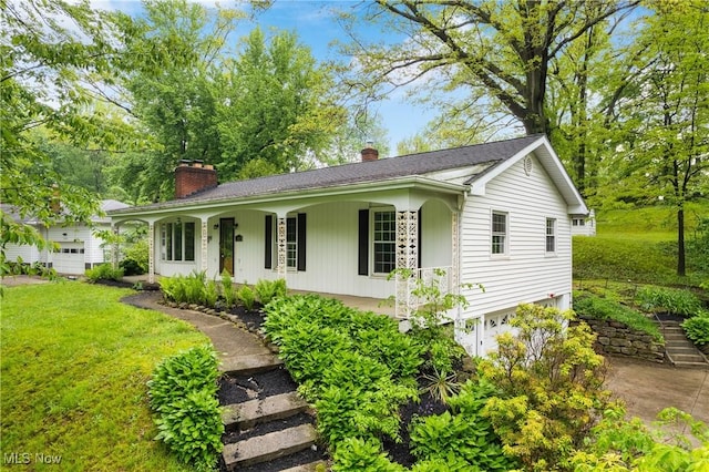 ranch-style house featuring a chimney, a porch, an attached garage, and a front yard