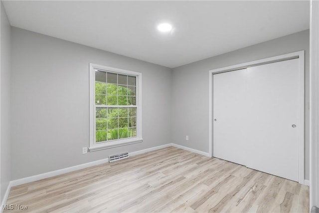 unfurnished bedroom with light wood-style floors, a closet, and baseboards