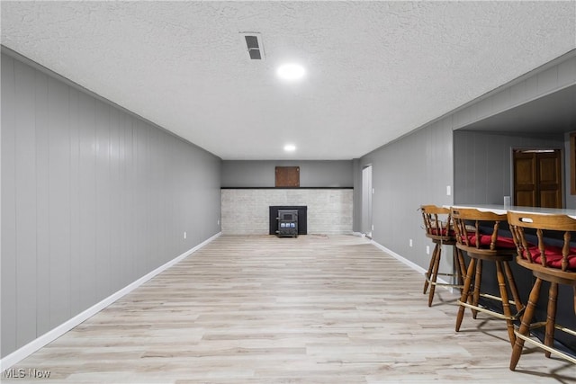 living room with wood finished floors, a bar, a textured ceiling, and baseboards