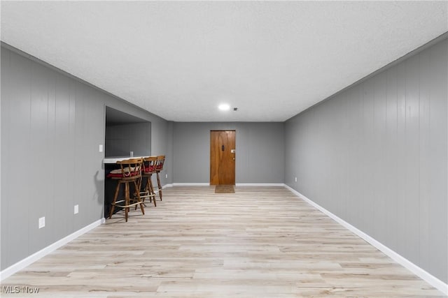 living room with wood finished floors, baseboards, and a bar