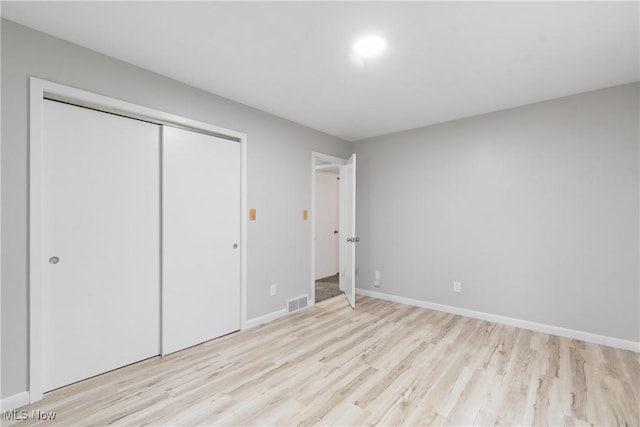unfurnished bedroom featuring light wood finished floors, a closet, and baseboards