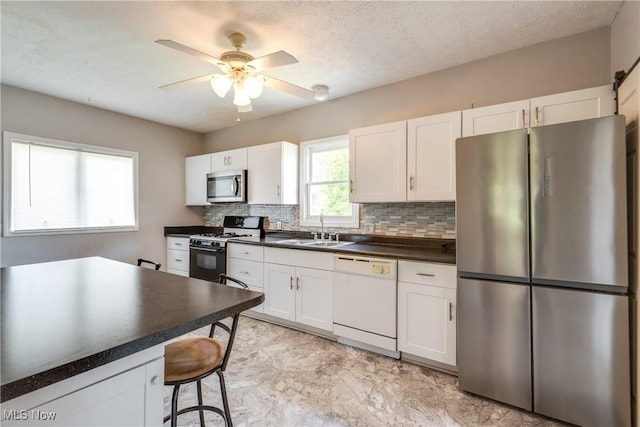 146 E Bergey St, Wadsworth, OH 44281 - kitchen with appliances with stainless steel finishes, a sink, dark countertops, decorative backsplash, and a ceiling fan