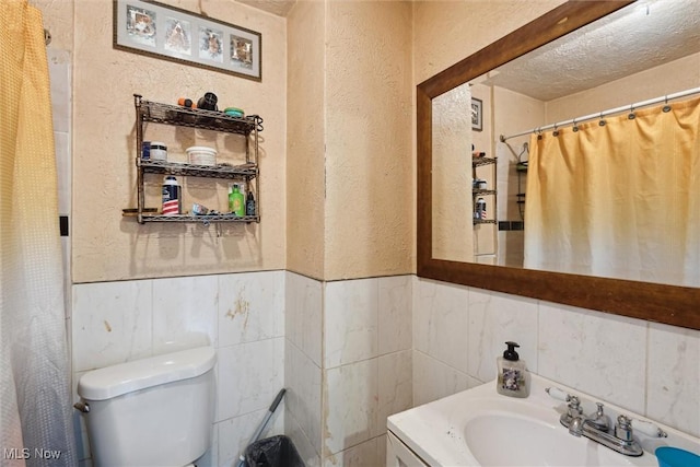 3074 Erin Ave, Cleveland, OH 44113 - bathroom with a textured wall, toilet, tile walls, a textured ceiling, and wainscoting