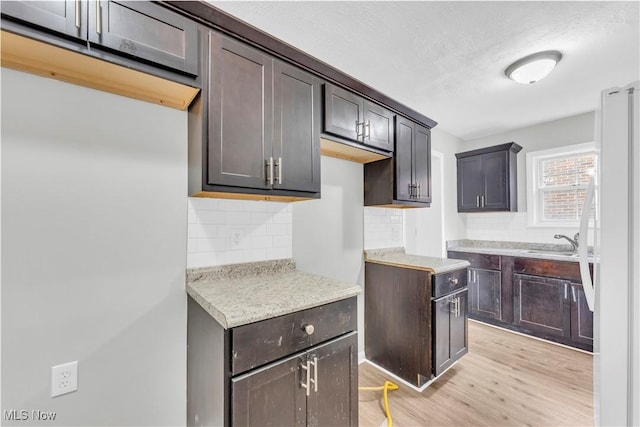 563 E 260th St, Euclid, OH 44132 - kitchen featuring decorative backsplash, light wood-style floors, freestanding refrigerator, dark brown cabinets, and a sink