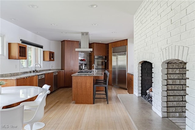 2471 Snowberry Ln, Pepper Pike, OH 44124 - kitchen featuring stainless steel appliances, island range hood, a breakfast bar, brown cabinetry, and a center island