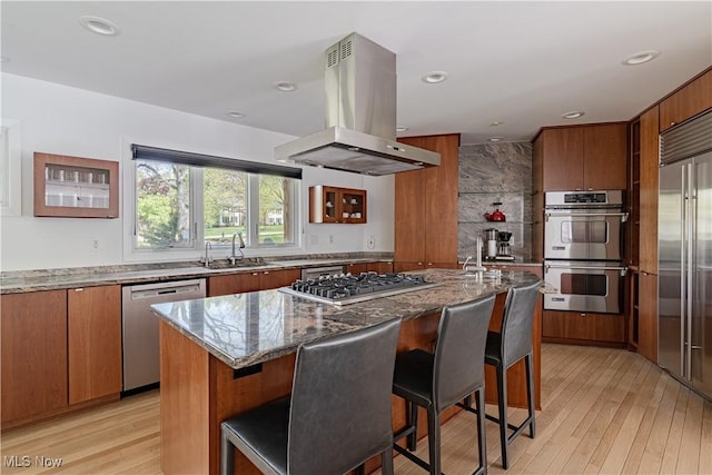 2471 Snowberry Ln, Pepper Pike, OH 44124 - kitchen with appliances with stainless steel finishes, island range hood, brown cabinets, light wood finished floors, and light stone counters