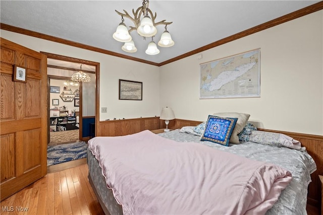 41972 Griswold Rd, Elyria, OH 44035 - bedroom featuring a chandelier, a wainscoted wall, light wood-style floors, wood walls, and ornamental molding
