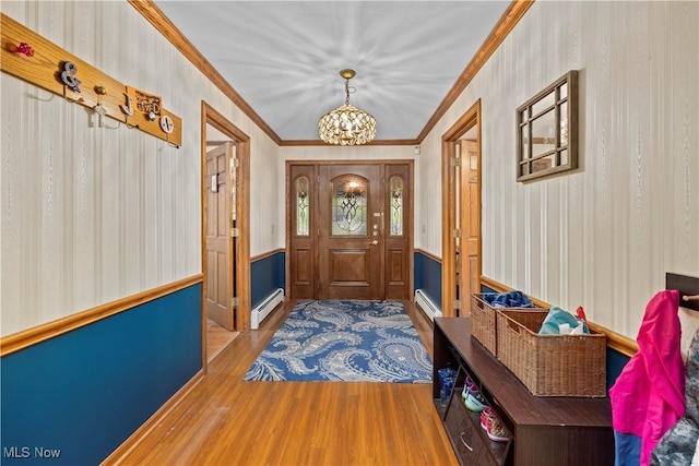 41972 Griswold Rd, Elyria, OH 44035 - foyer entrance featuring a baseboard heating unit, a chandelier, wainscoting, wood finished floors, and crown molding