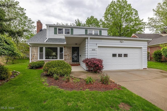 2639 Whiton Rd, University Heights, OH 44118 - traditional-style home featuring concrete driveway, stone siding, a chimney, an attached garage, and a front yard