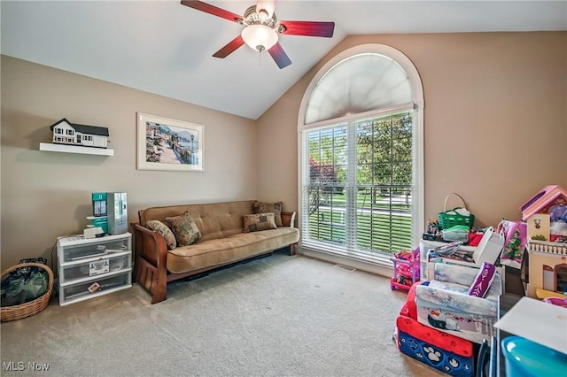 carpeted living area with ceiling fan and vaulted ceiling