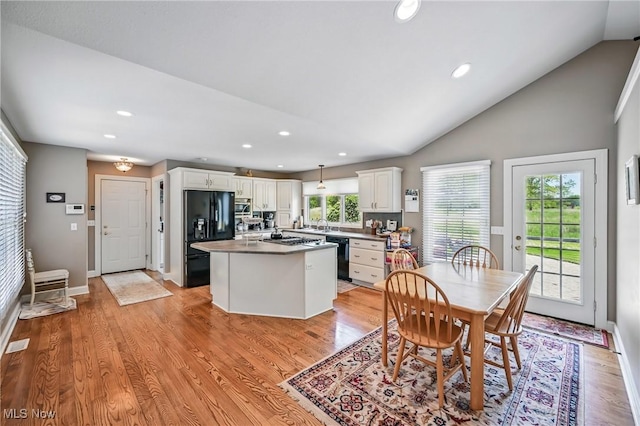 kitchen featuring black appliances, white cabinetry, a center island, vaulted ceiling, and light wood-style floors