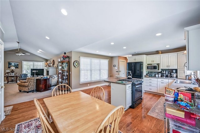 kitchen with range with gas cooktop, a sink, freestanding refrigerator, stainless steel microwave, and white cabinetry
