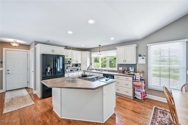 kitchen with black fridge with ice dispenser, white cabinetry, light wood finished floors, stainless steel gas cooktop, and recessed lighting