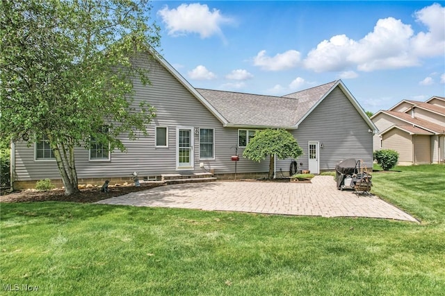 rear view of house with a patio, a yard, and roof with shingles