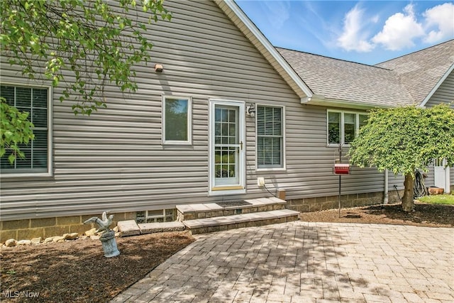 back of property with a shingled roof and a patio