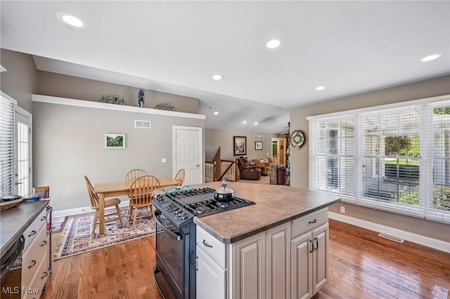 kitchen featuring black appliances, light wood-type flooring, baseboards, a center island, and recessed lighting