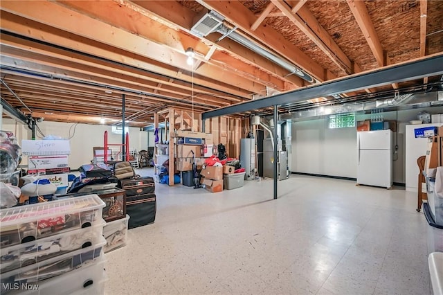 basement featuring freestanding refrigerator, water heater, heating unit, and tile patterned floors