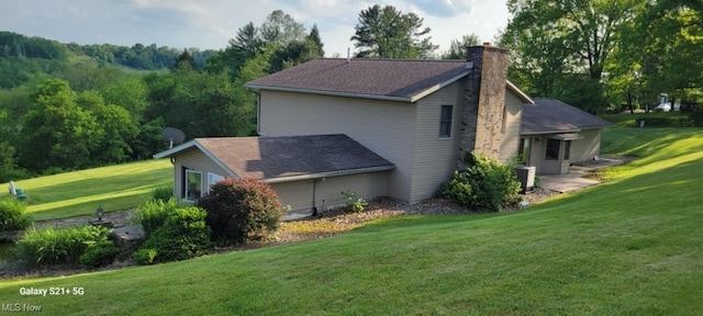 61426 Stillmeadow Ln, New Concord, OH 43762 - view of side of home featuring a chimney, a yard, and central AC