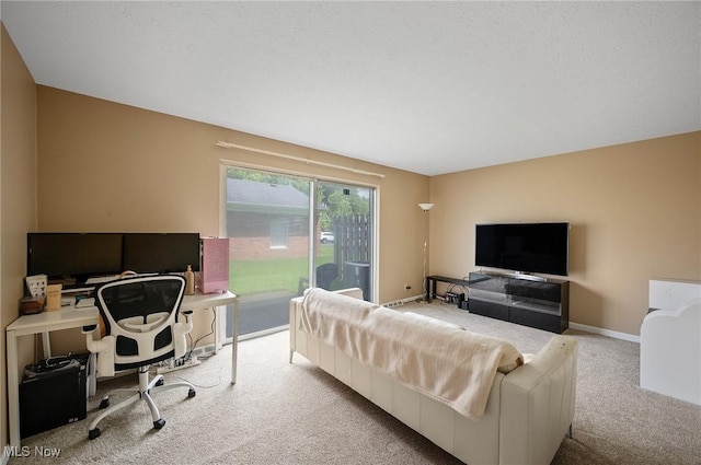 carpeted living area with a desk and baseboards