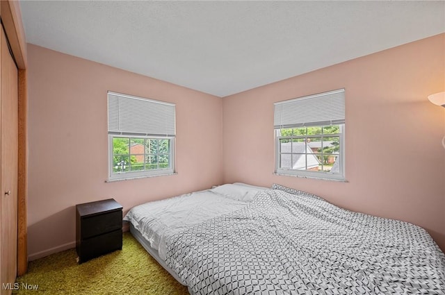 bedroom with multiple windows, carpet floors, and baseboards